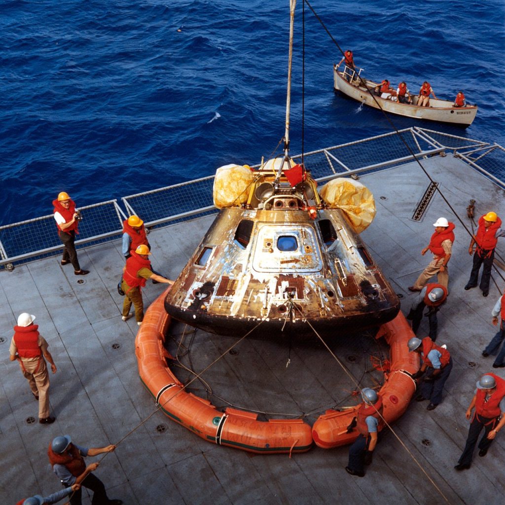 The Apollo 11 capsule is lowered onto the deck of the Hornet. Note the flotation ring attached by the divers. 